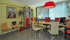 Un salón de conferencias con una gran mesa, varias sillas, una estantería y un cuadro en la pared.
