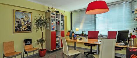 Un salón de conferencias con una gran mesa, varias sillas, una estantería y un cuadro en la pared.