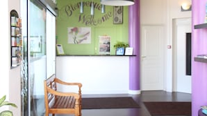 A reception area with a wooden bench, a green wall with a 'Welcome' sign, and a door in the background. - Hotel d Orléans (Angouleme)