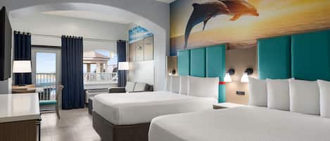 A hotel room with two beds, a desk, and a balcony view.