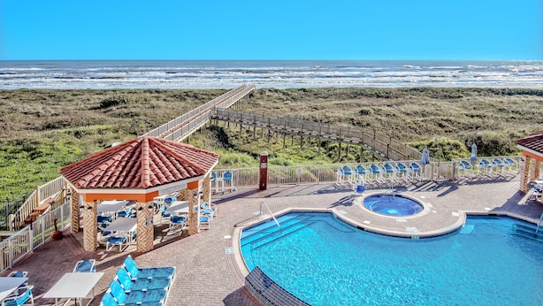 A pool area with a gazebo, lounge chairs, and a view of the ocean. - La Copa Inn Beach Hotel (South Padre Island)