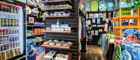 Una tienda con estantes llenos de diversos artículos, incluyendo sombreros, zapatos y accesorios de playa.