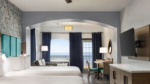A hotel room with two beds, a desk, a chair, a TV, and a balcony with curtains. - La Copa Inn Beach Hotel (South Padre Island)