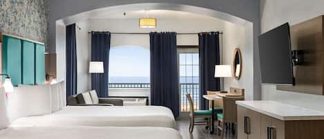Une chambre d’hôtel avec deux lits, un bureau, une chaise, une télévision et un balcon avec des rideaux.