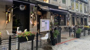A restaurant named 'Mur Mur Resto' with outdoor seating, a menu board, and a sign for 'Hotel Ste-Anne' in the background. - Hôtel Sainte-Anne (Québec City)