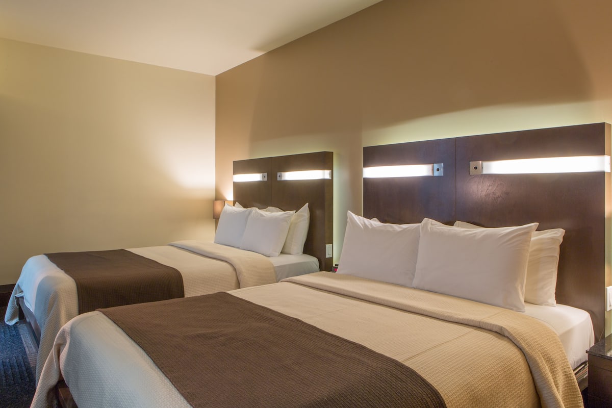 Une chambre d’hôtel avec deux lits, chacun doté d’une tête de lit et de lampes de chevet.