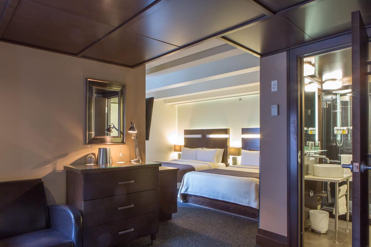 Une chambre d’hôtel comprenant un lit, une commode, un miroir et une salle de bain avec un lavabo et une douche.