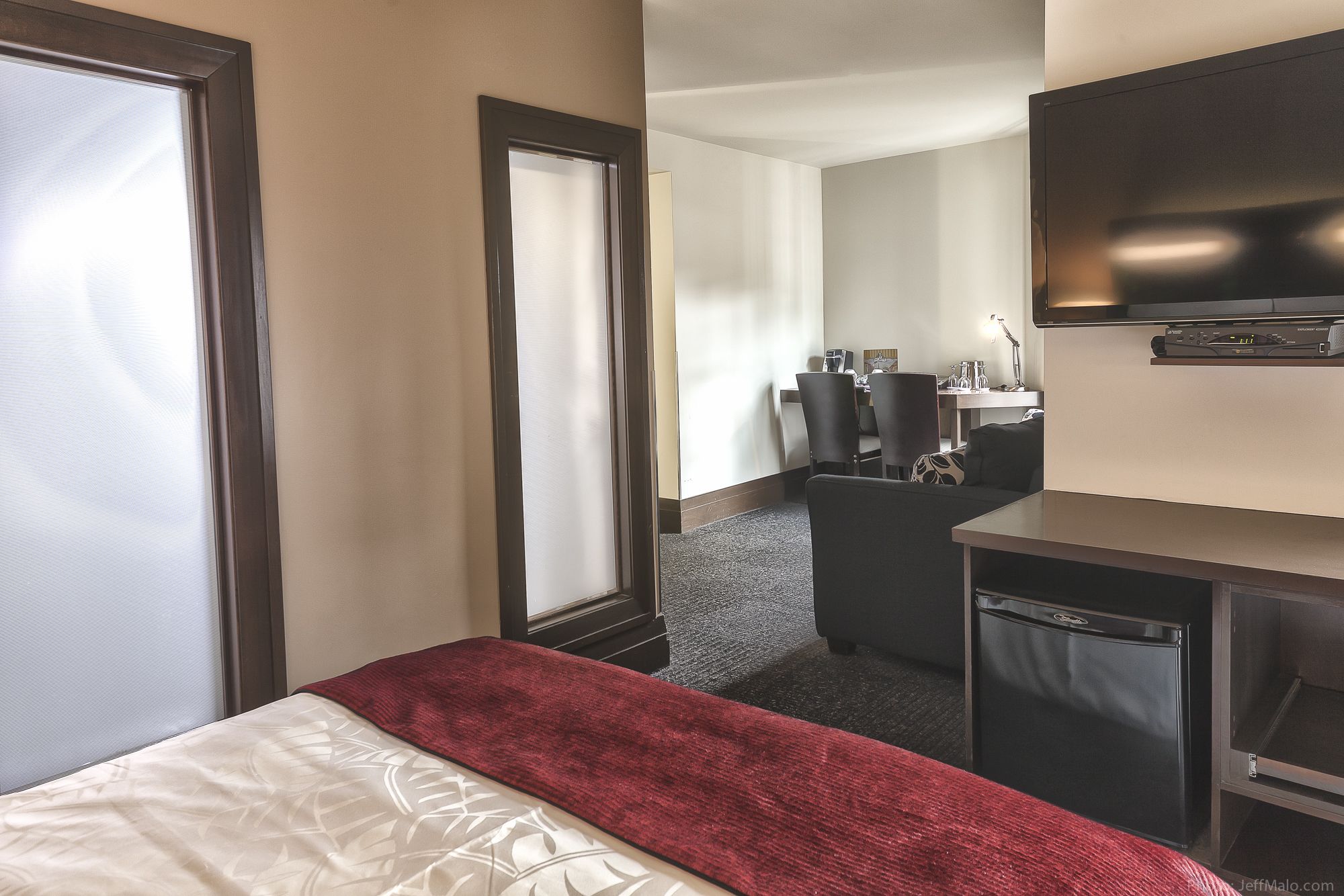 Een hotelkamer met een bed, een bureau, een stoel, een televisie en een minibar.