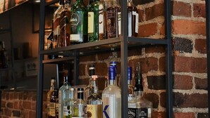 A bar area with shelves stocked with various liquor bottles and hanging glasses. - Hôtel Sainte-Anne (Québec City)