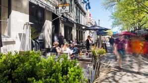 An outdoor seating area of Le Grill Ste-Anne with tables and chairs, a flag, and a clear sky. - Hôtel Sainte-Anne (Québec City)