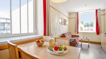 Ein modernes Wohnzimmer mit einem Holzesstisch, einer Couch und einem Fenster mit roten Vorhängen.