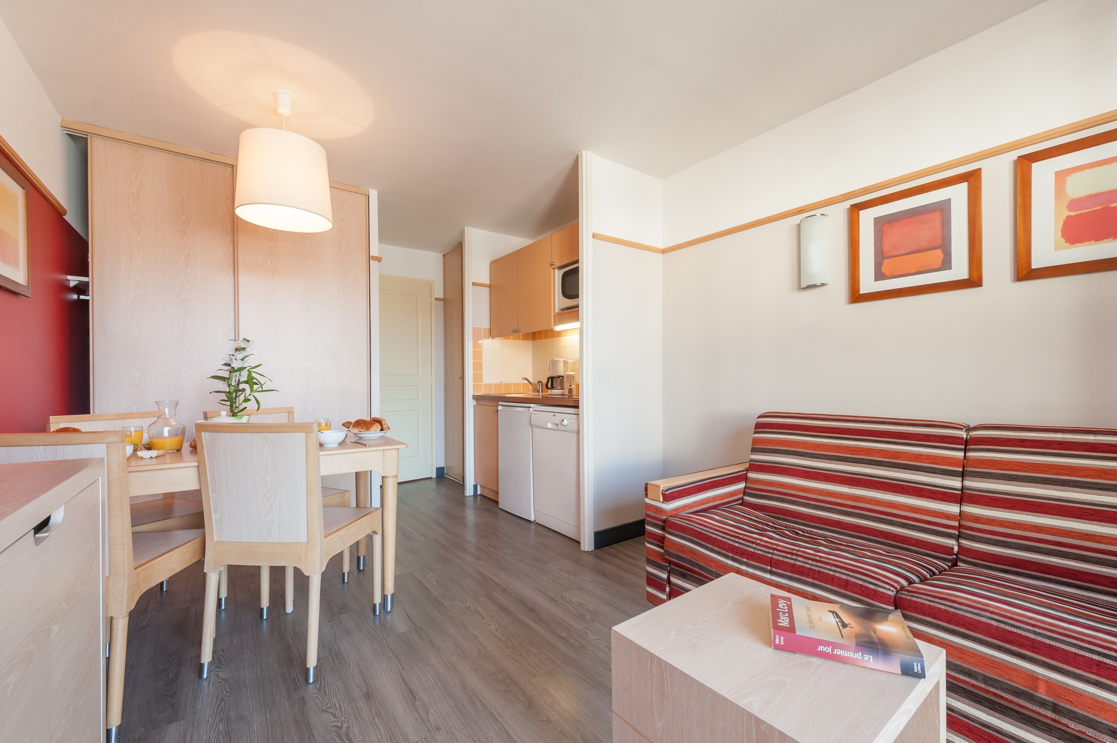 Un espace de vie compact comprenant un coin repas, une kitchenette et un canapé à rayures.