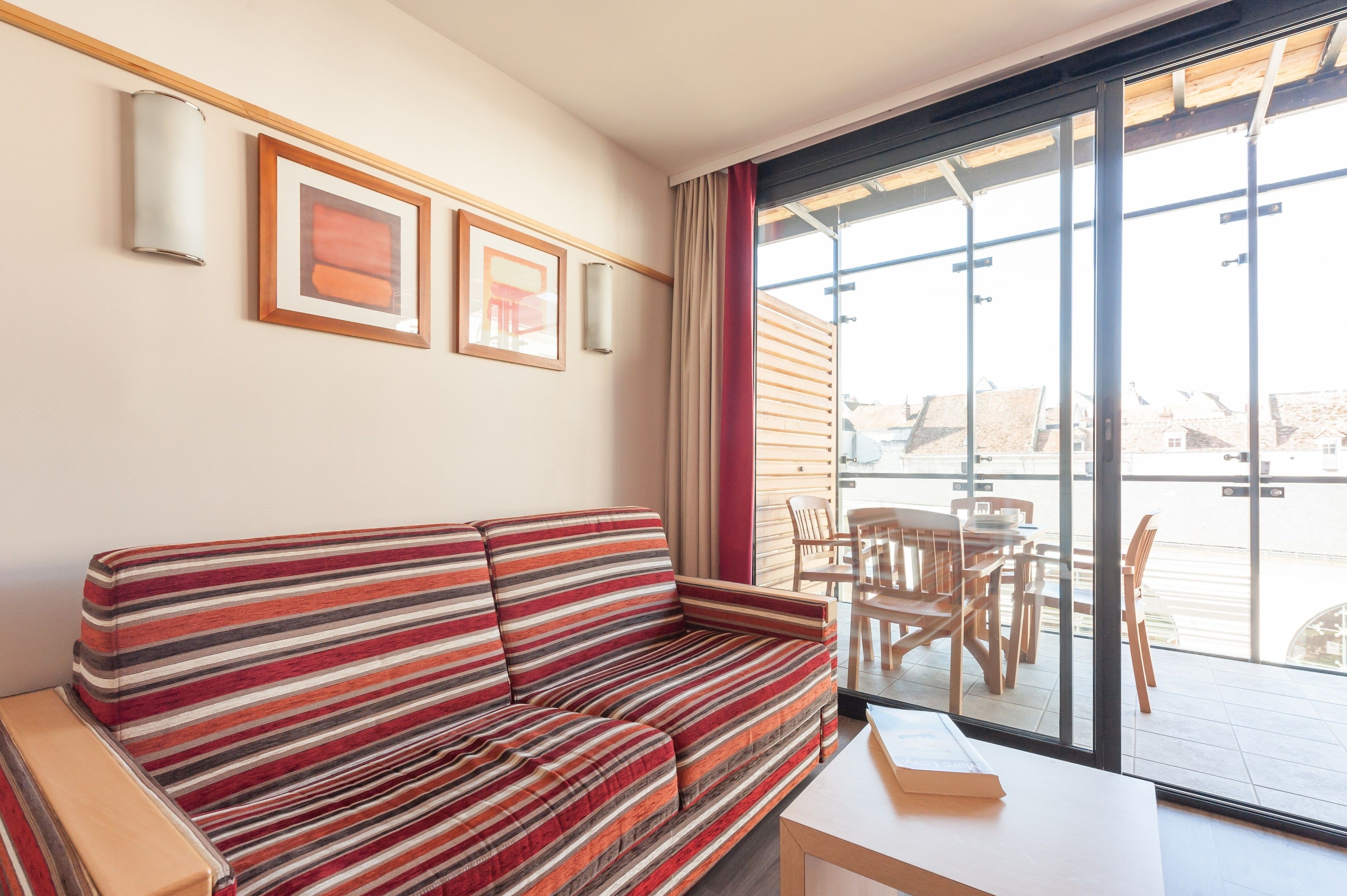 A striped sofa, a table, and a view of the outside through large windows.