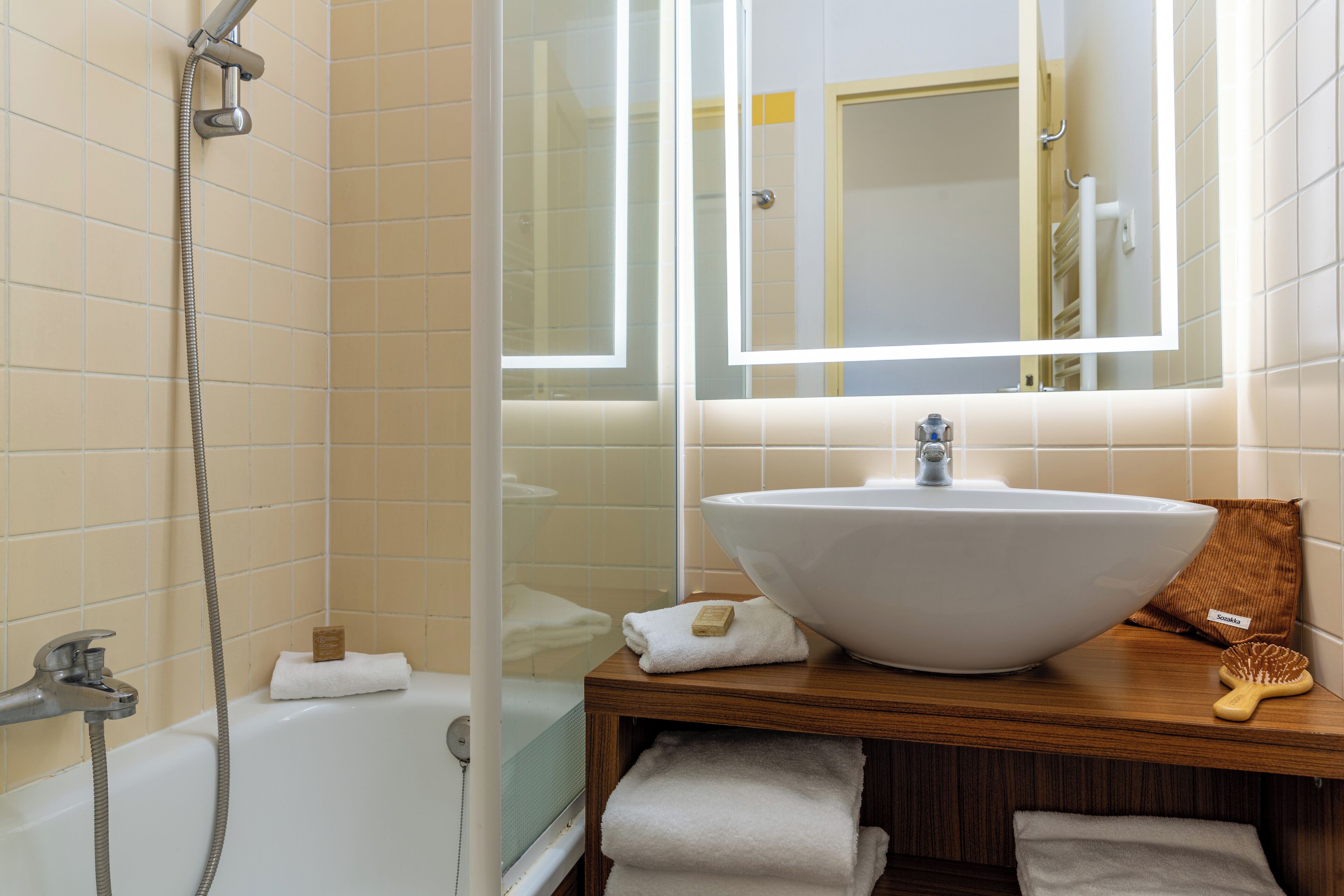 A bathroom with a bathtub, a large sink, a mirror, and a shower.
