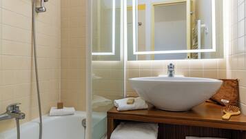 A bathroom with a bathtub, a large sink, a mirror, and a shower.