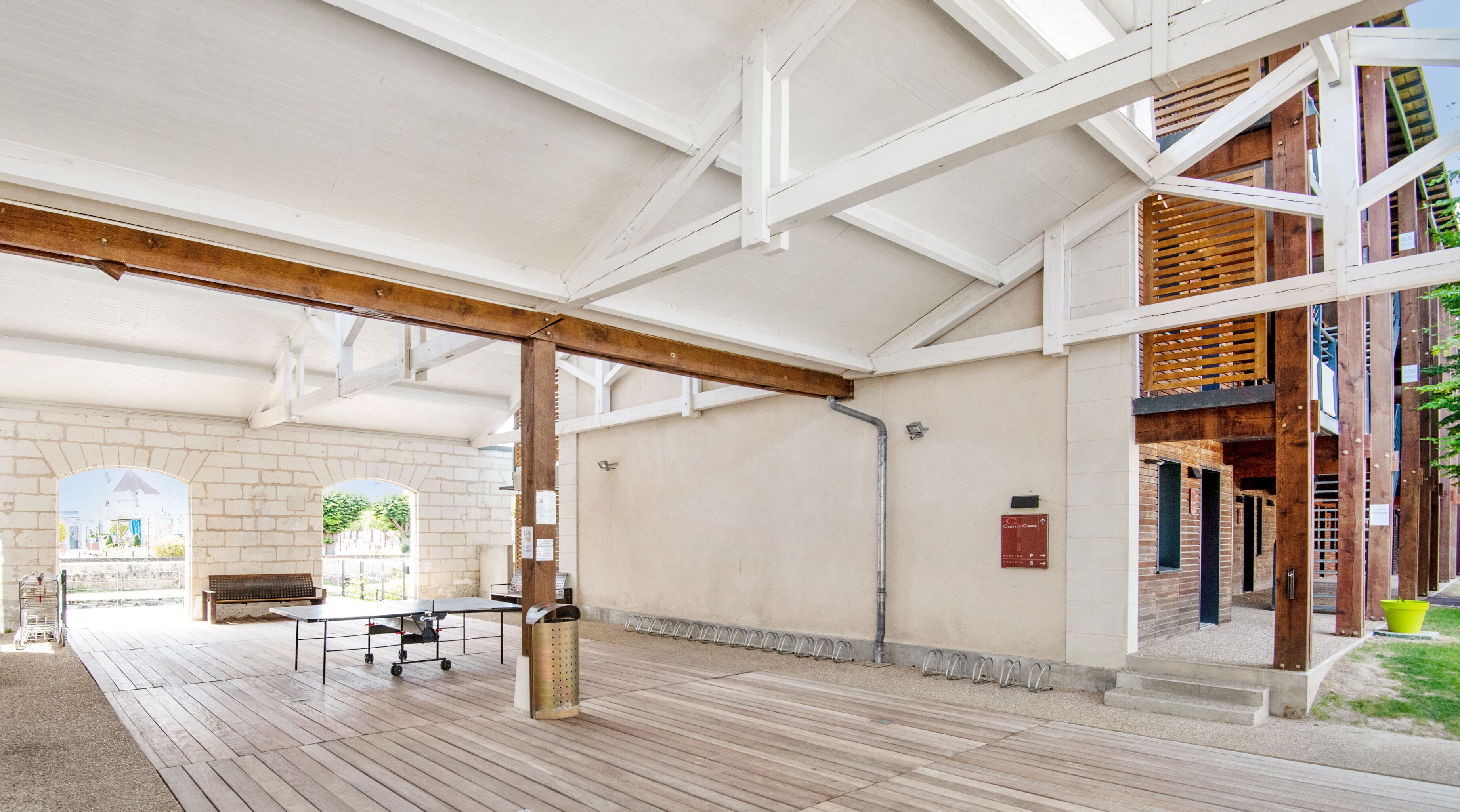 An open-plan area with a wooden deck, a table, and a bench.