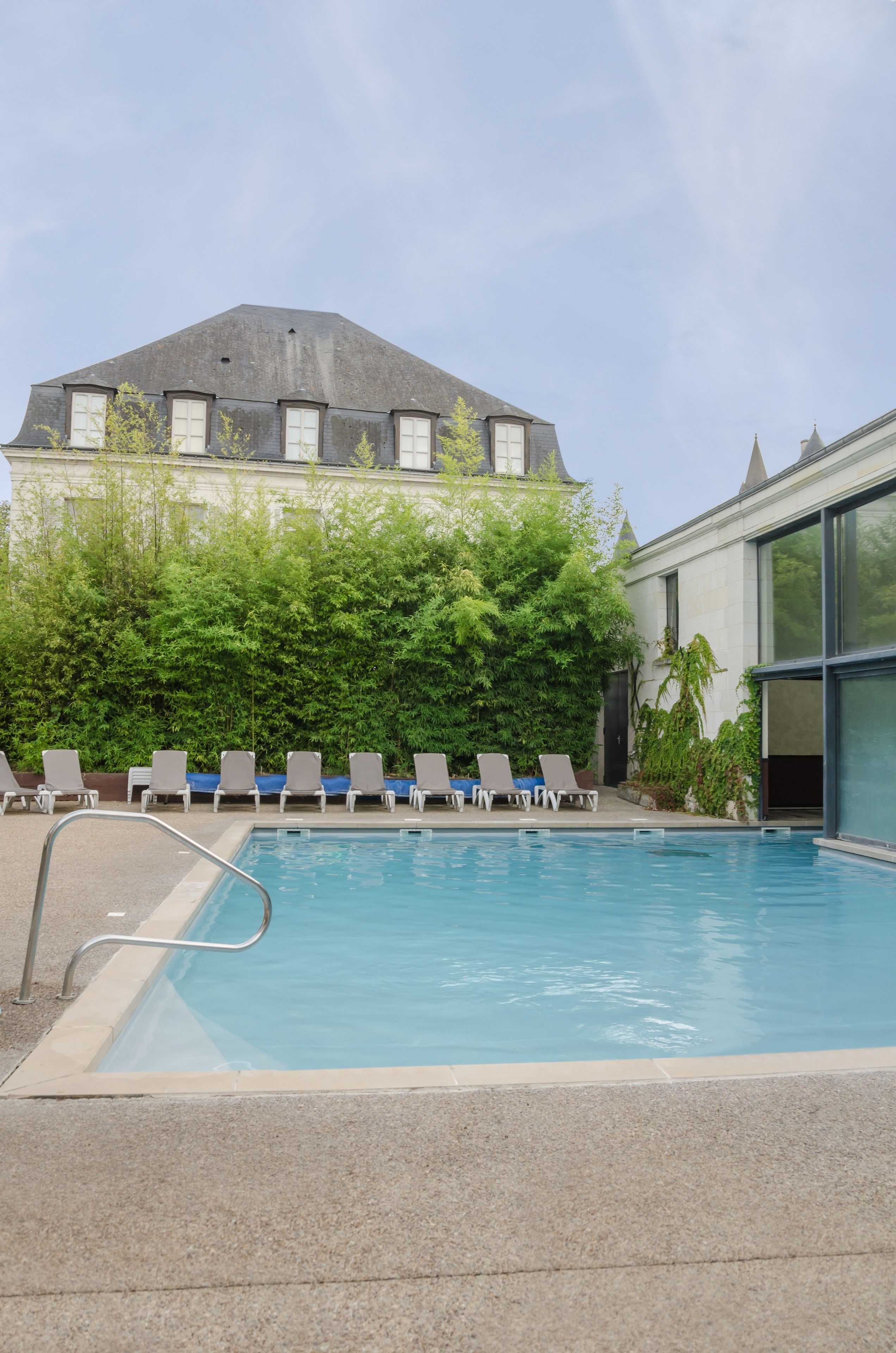A swimming pool with lounge chairs and a building in the background.