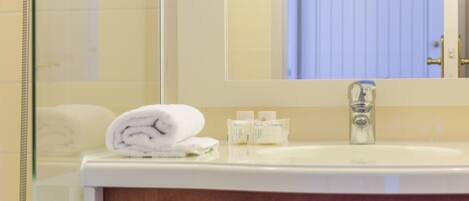 A bathroom with a white sink, a mirror, and a towel on the counter.