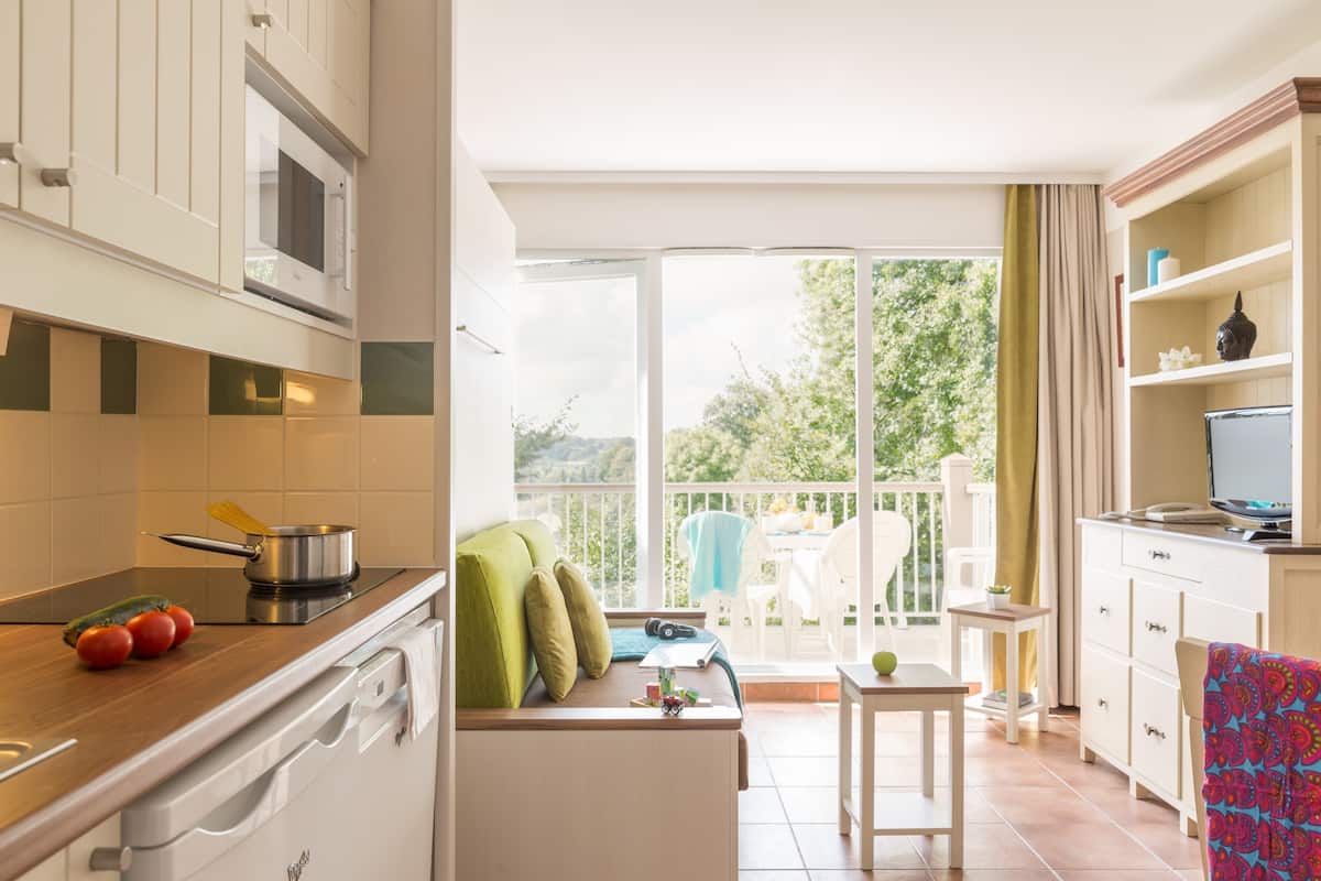 Een moderne keuken met een eethoek, een balkon met een tafel en stoelen, en een televisie op een kast.