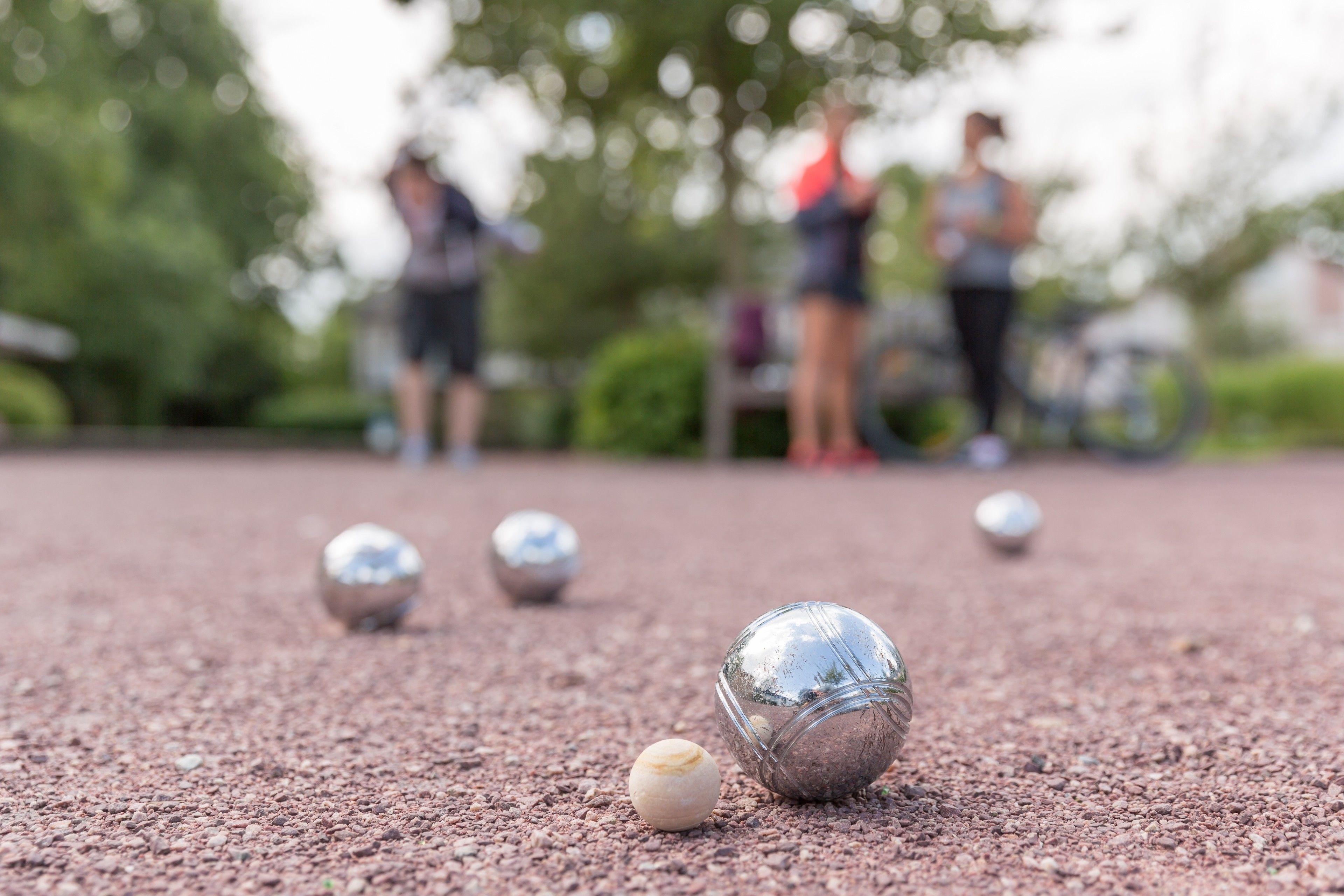 A close-up of a croquet ball on a gravel surface with other balls in the background.