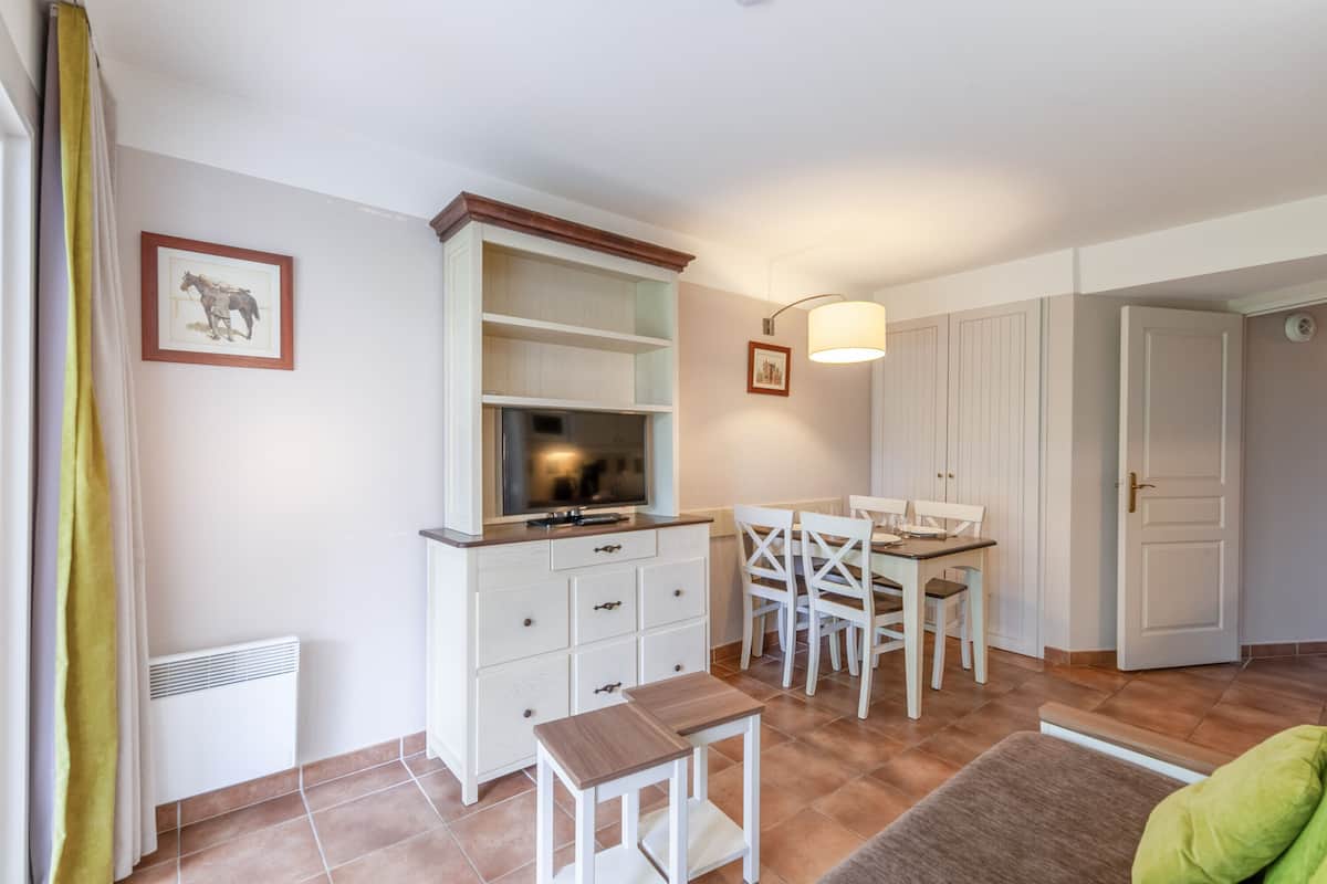 Een kamer met een eettafel, stoelen, een televisie en een deur.