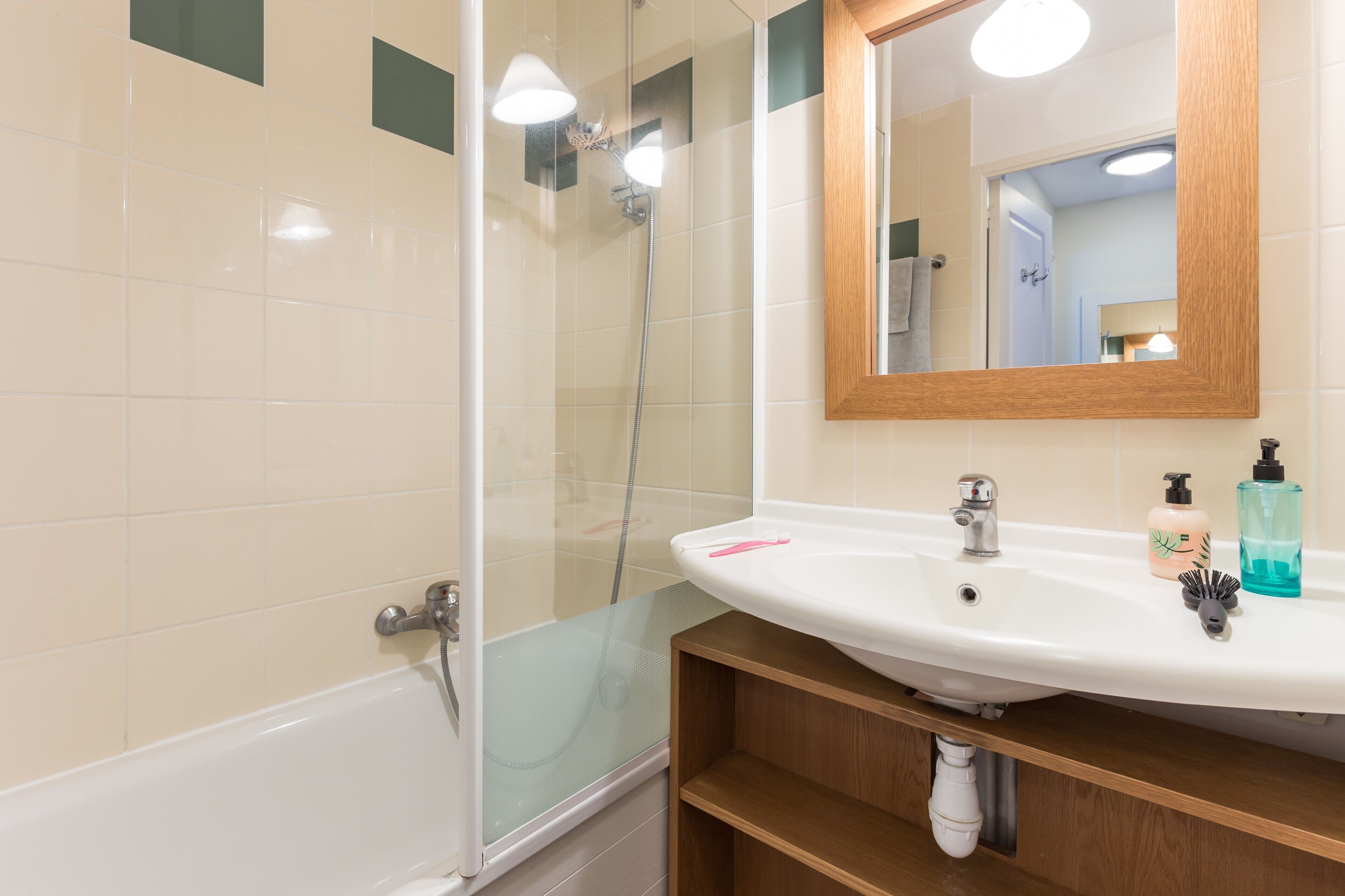 Un baño con ducha, lavamanos y espejo.