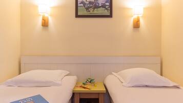A hotel room with two beds, a nightstand with a lamp, and a framed picture on the wall.