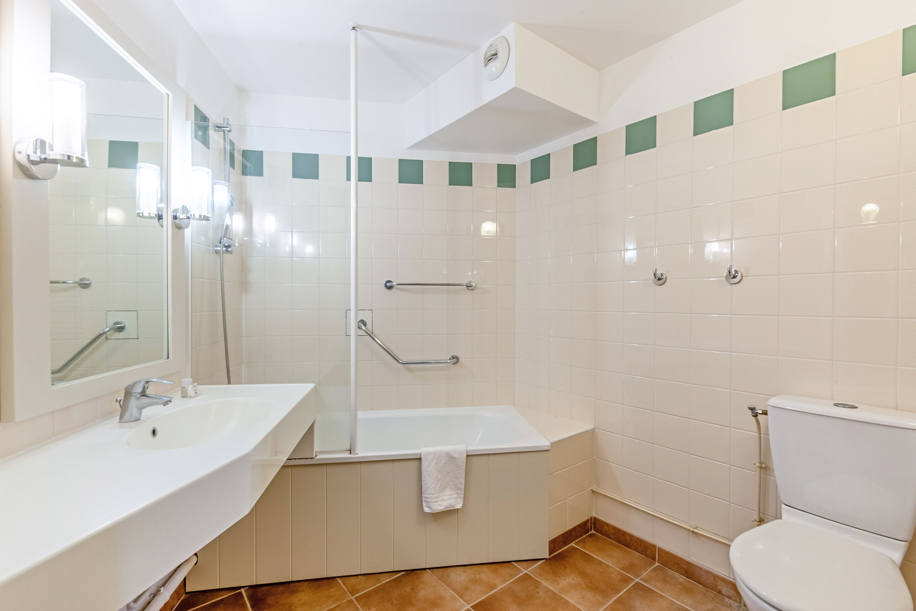 Une salle de bain équipée d’un lavabo, d’un miroir, d’une baignoire, d’une douche et de toilettes.