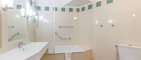Une salle de bain équipée d’un lavabo, d’un miroir, d’une baignoire, d’une douche et de toilettes.