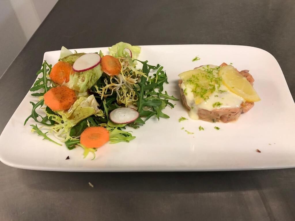 Een rechthoekig wit bord met een salade en een sandwich.
