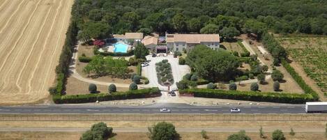 An aerial view of a hotel with a swimming pool, a restaurant, and a well-maintained garden.