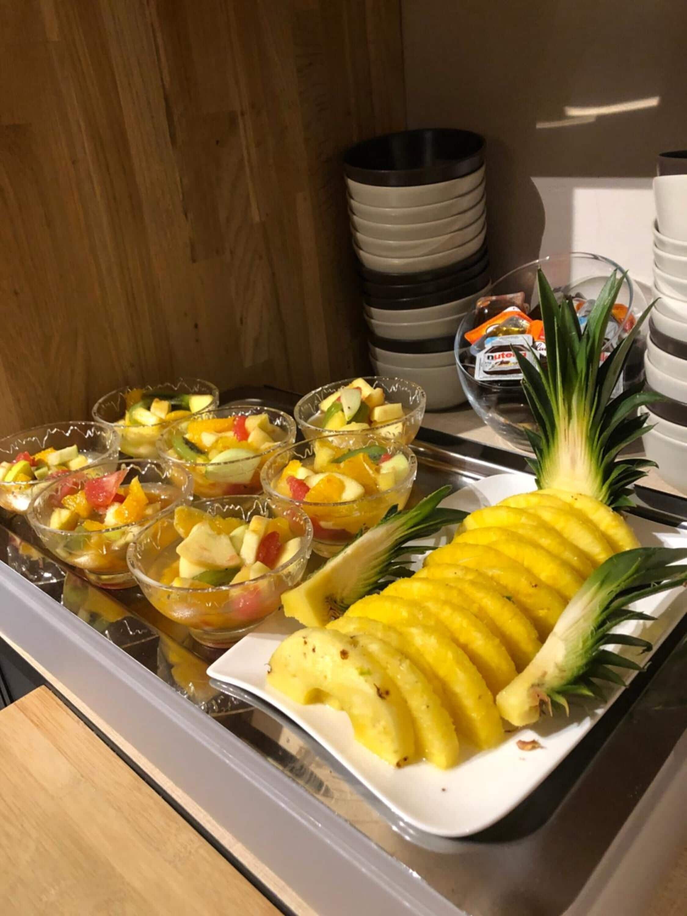 Un buffet avec des saladiers de fruits et un ananas sur un plateau.