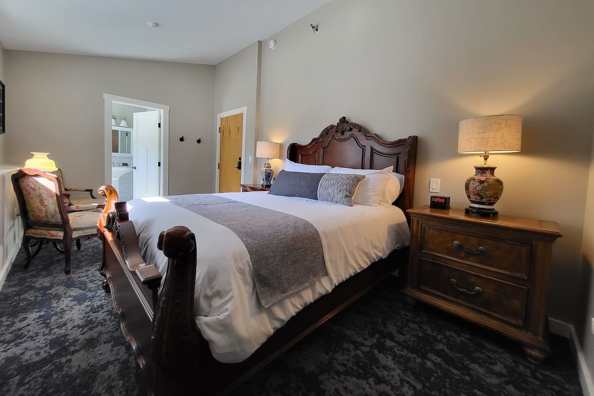 A neatly arranged bedroom with a large bed, bedside tables, a chair, and a dresser.