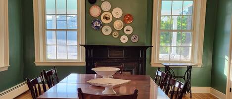 A dining room with a wooden table and chairs, a fireplace, and a wall decorated with plates.