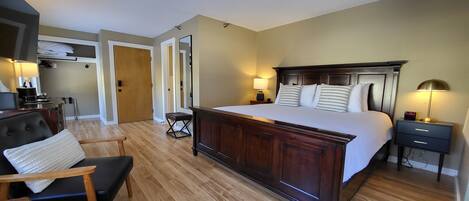 A hotel room with a large bed, bedside tables, a desk, and a chair.