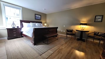 A bedroom with a large bed, a bedside table with a lamp, a chair, and a small table with a lamp.
