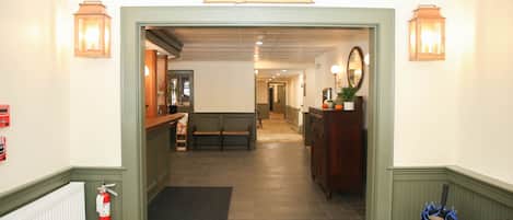 A hotel lobby with a 'WELCOME' sign, a fire extinguisher, a bench, a radiator, and a water dispenser.