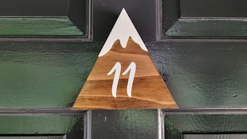 Segnaletica in legno con la cima di una montagna e il numero 11 su una porta.