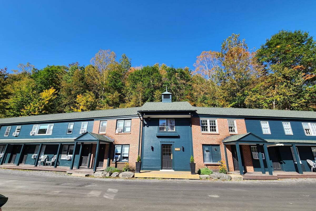 A two-story building with a central entrance, multiple windows, and a parking lot in front.
