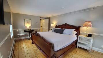A bedroom with a wooden bed, a bedside table with a lamp, a chair, and a wardrobe.