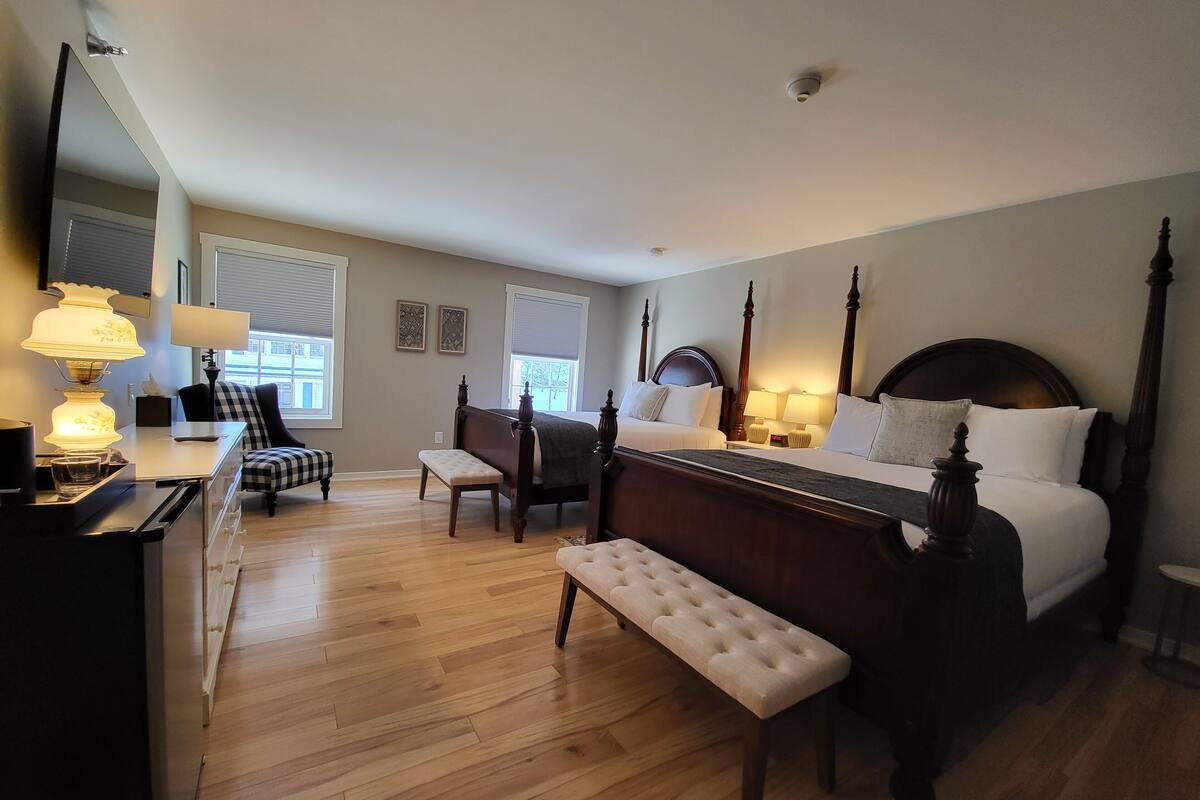 A bedroom with a four-poster bed, a bench, a desk with a lamp, and a chair.