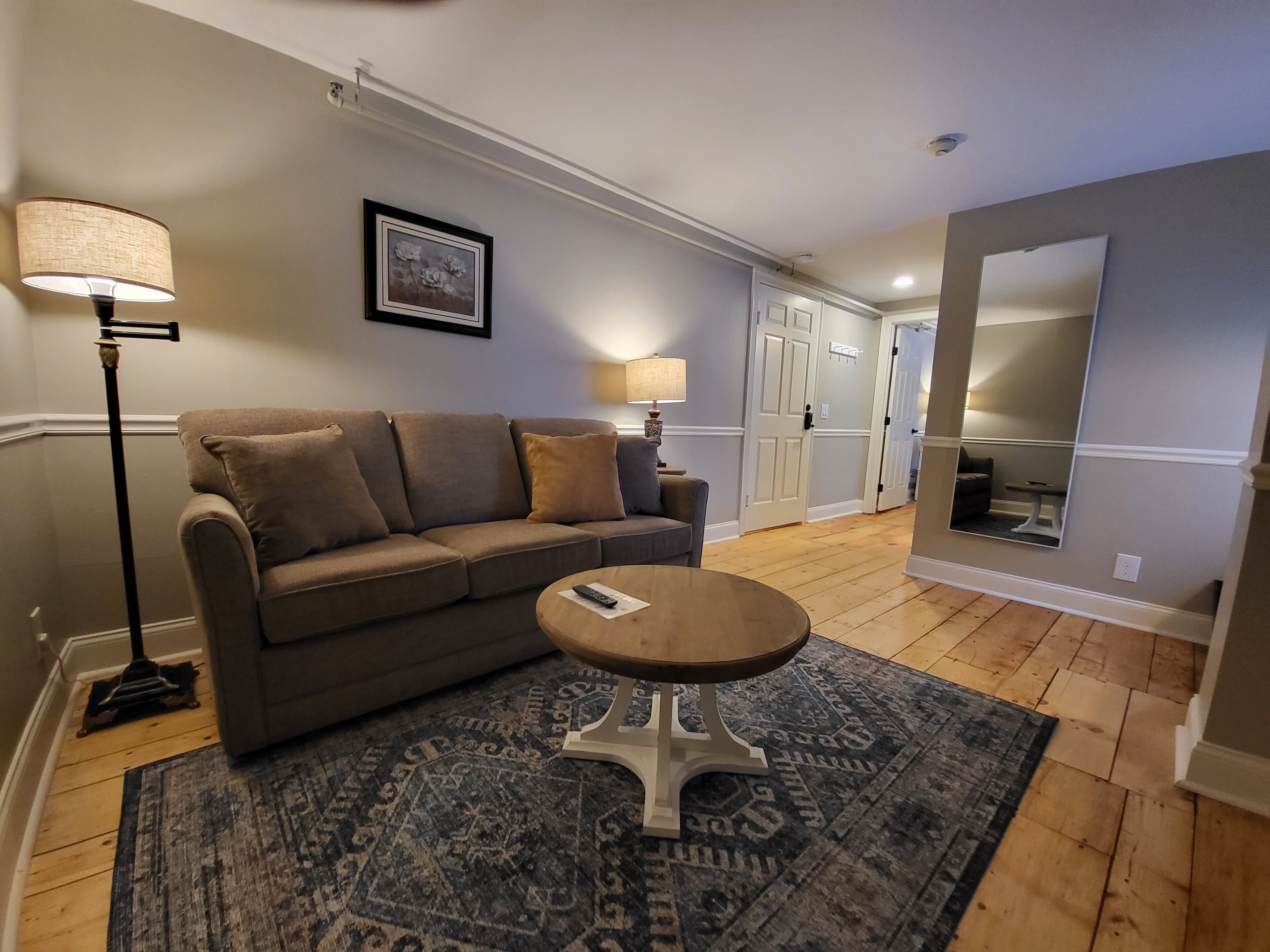 A living room with a sofa, a coffee table, a rug, a lamp, and a framed picture on the wall.