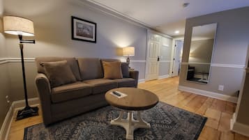A living room with a sofa, a coffee table, a rug, a lamp, and a framed picture on the wall.