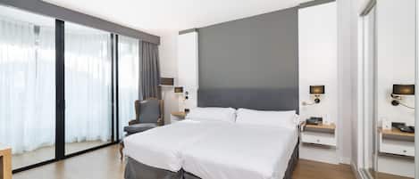 A modern hotel room with a large bed, a desk, and a chair.