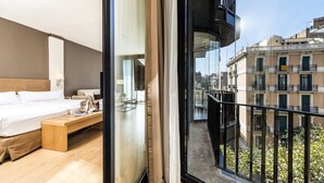 A modern hotel room with a large bed, a wooden bench, and a balcony with a city view. - Guitart Grand Passage (Barcelona)