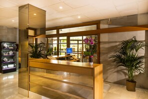 A reception desk with a computer, a plant, and a display case with jewelry.