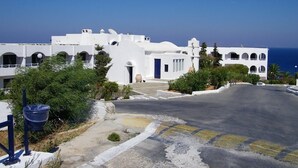 A white building with multiple arches and a clear view of the sea. - Esperides Apartments (Malevizi)