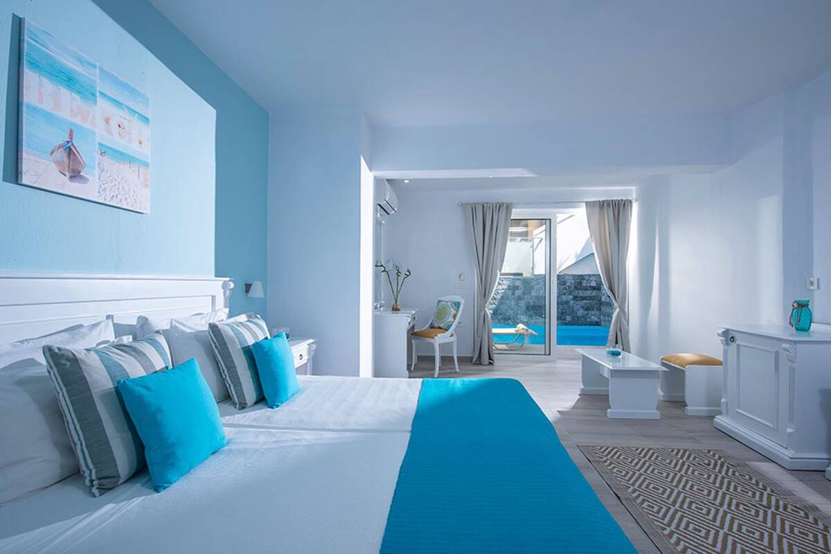 A modern hotel room with a large bed, a view of the sea, and a balcony.