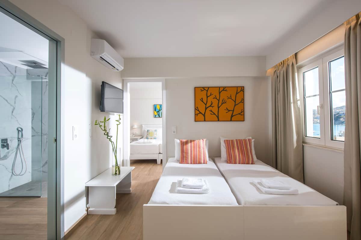 A modern hotel room with a large bed, a TV, a painting, and a view of the city.