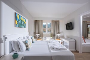 Habitación de hotel con una cama grande, un escritorio, una silla, un televisor y una ventana con cortinas.